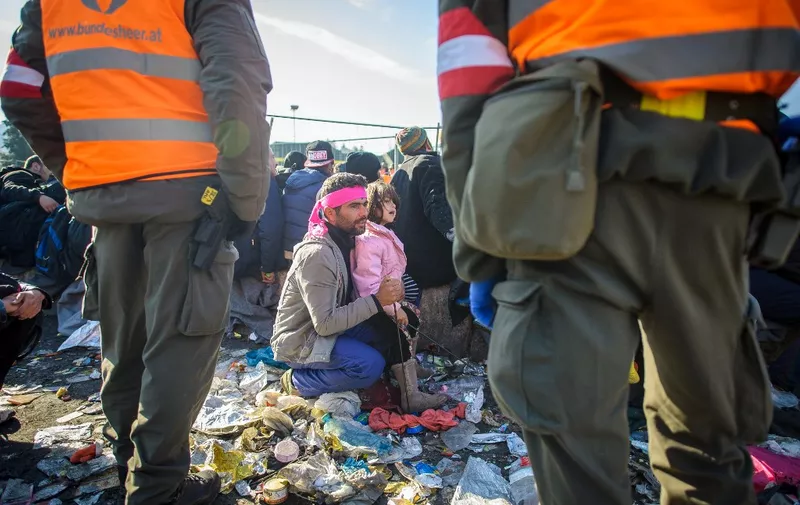 A migrant holds his child as refugees and migrants wait to cross the Slovenian-Austrian border from the Slovenian city of Sentilj, on November 3, 2015. Austria's government, facing a record influx of migrants as well as a surge in support for the anti-immigration far-right, moved on November 3, 2015 to tighten asylum rules in the EU country. Austria has seen some 400,000 migrants enter the country since September, most of whom travel onwards to Germany or Scandinavia. AFP PHOTO / RENE GOMOLJ (Photo by Rene Gomolj / AFP)
