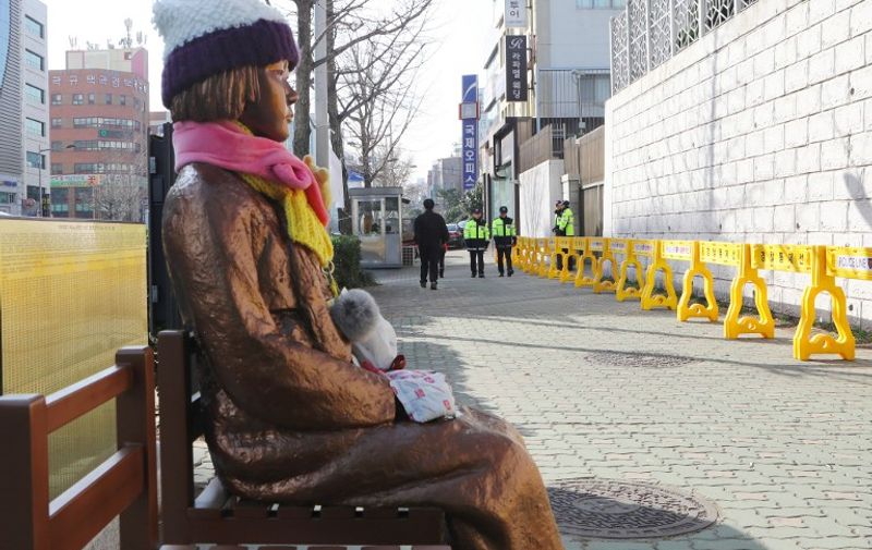 This picture taken on January 2, 2017 shows a statue (L) of a teenage girl symbolizing "comfort women" who served as sex slaves for Japanese soldiers during World War II, outside the Japanese consulate in Busan. 
Japan said on January 6 that it had decided to temporarily recall its ambassador to South Korea to protest the placing of a statue symbolising victims of Japanese wartime sex slavery outside its consulate in the city of Busan last month. / AFP PHOTO / YONHAP / STR / South Korea OUT / REPUBLIC OF KOREA OUT  NO ARCHIVES  RESTRICTED TO SUBSCRIPTION USE