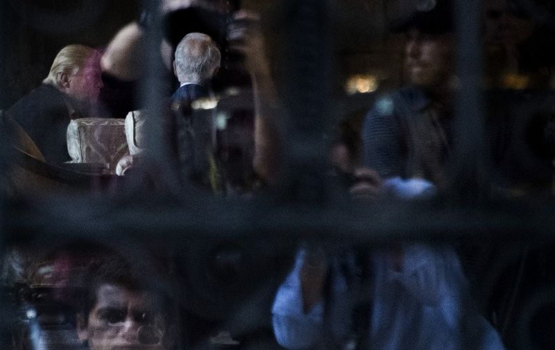 US President-elect Donald Trump (L) is seen through the glass of a side door at his Mar-a-Lago estate in Palm Beach, Florida, where he is holding meetings on December 21, 2016. / AFP PHOTO / JIM WATSON