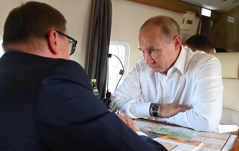 Russian President Vladimir Putin (R) speaks with Russian Ural Federal District, Chelyabinsk Region Governor Alexei Teksler (L), aboard a helicopter as they survey damage from wildfires in some areas of the Chelyabinsk Region, Russia, on August 6, 2021. (Photo by Alexey NIKOLSKY / SPUTNIK / AFP)