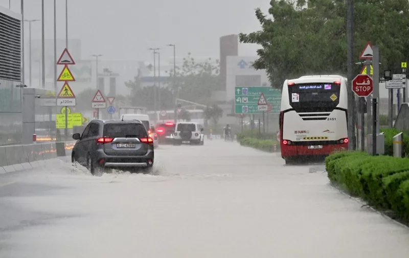 Vehicles drive on a flooded road during torrential rain in the Gulf Emirate of Dubai on April 16, 2024. Torrential rains and high winds lashed parts of the Gulf on April 16, as the death toll from storms in Oman rose to 18, many of them children. Flights were cancelled in Dubai, the region's financial hub, while schools were shut in the United Arab Emirates and Bahrain. (Photo by Giuseppe CACACE / AFP)