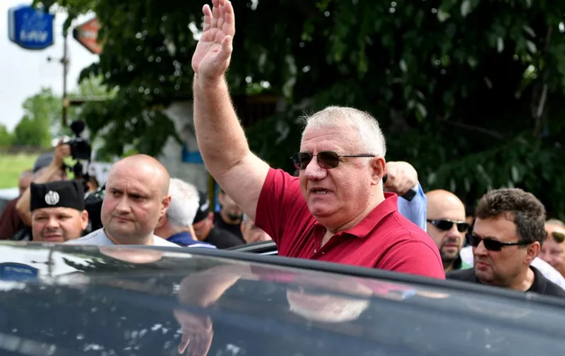 Serbian Radical Party leader Vojislav Seselj (C), waves to his supporters, as strong police presence stopped him in the village of Jarak near Hrtkovci on May 6, where he planned a rally on the anniversary of his inflammatory anti-Croat speech in 1992 that led to his conviction by the UN war crimes court in The Hague. - Large number of Serbian police forces blocked on Sunday all access to the village, located 70 kilometres west of Belgrade. "We have come to provoke the regime that forbids us to manifest what is our legitimate right as an opposition and not the Croats" who live in Hrtkovci, said Vojislav Seselj, 63 years old to journalists in the village of Jarak, located in 3 km from Hrtkovci, where a cordon of police barred the road. (Photo by ANDREJ ISAKOVIC / AFP)