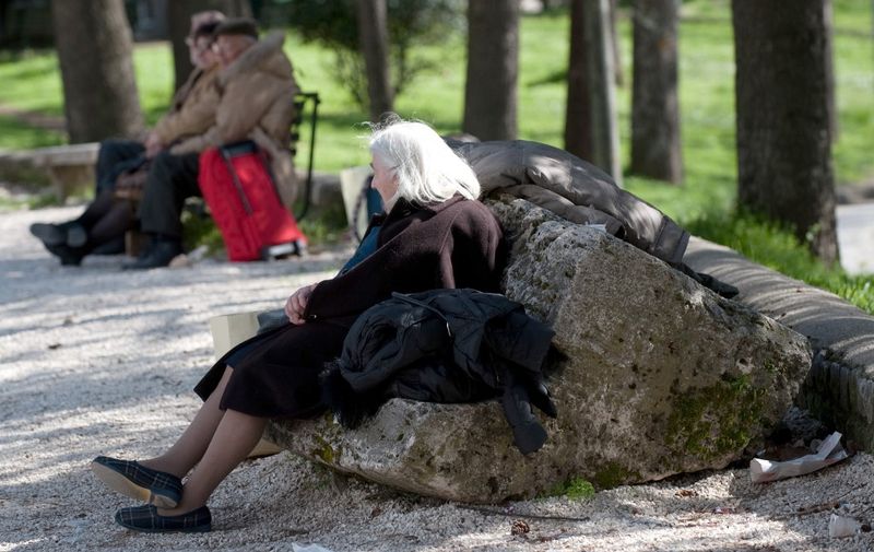 Elderly people wait for assistance with their belongings in a public garden of the old city of the Abruzzo capital L'Aquila, epicentre of an earthquake on April 6, 2009.  A violent earthquake jolted central Italy killing at least 100 people and injuring 1,500 as buildings and homes in the walled medieval town of L'Aquila were reduced to rubble.  AFP PHOTO / CHRISTOPHE SIMON (Photo by CHRISTOPHE SIMON / AFP)
