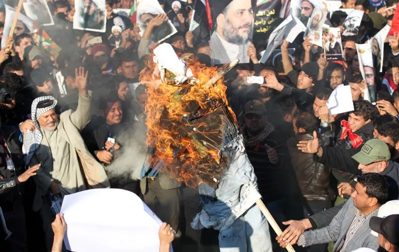 Supporters of Iraqi Shiite cleric Moqtada al-Sadr (portrait top-C) burn a effigy of a member of the Saudi ruling family as others hold posters of prominent Shiite cleric Nimr al-Nimr during a demonstration in the capital Baghdad on January 4, 2016, against Nimr's execution by Saudi authorities. Sunni-ruled Saudi Arabia severed diplomatic ties with Shiite-dominated Iran, its long-time regional rival, after angry demonstrators attacked the Saudi embassy in Tehran and its consulate following Nimr's execution. AFP PHOTO / AHMAD AL-RUBAYE / AFP / AHMAD AL-RUBAYE