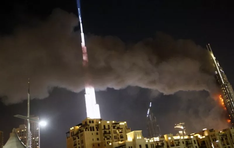 A picture taken on December 31, 2015 shows the Address Downtown hotel burning after huge fire ripped through the luxury hotel near the world's tallest tower, in Dubai. People were gathering to watch New Year's Eve celebrations when the hotel caught on fire without causing casualties, according to authorities. AFP PHOTO / KARIM SAHIB / AFP / KARIM SAHIB