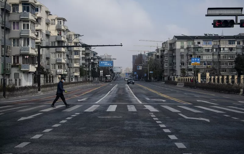 A man wearing a protective facemask walks on an empty street in Hangzhou, some 175 kilometres (110 miles) southwest of Shanghai on February 5, 2020, near Alibaba headquarters. - The world has a "window of opportunity" to halt the spread of a deadly new virus, global health experts said, as the number of people infected in China jumped to 24,000 and millions more were ordered to stay indoors. (Photo by NOEL CELIS / AFP)