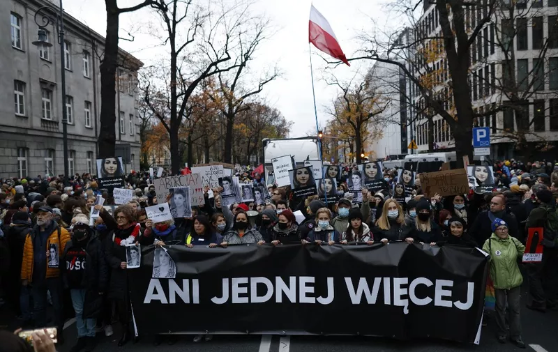 Protesters hold a banner reading "not even one more" as people take part in a demonstration on November 6, 2021 in Warsaw, Poland, to mark the first anniversary of a Constitutional Court ruling that imposed a near-total ban on abortion, and also to commemorate the death of pregnant Polish woman Iza. - Poland's Constitutional Court in 2020 sided with the Catholic country's populist right-wing government to rule that terminations over foetal defects were unconstitutional. This resulted in a further tightening of already heavy restrictions on abortions and thousands of women have sought help abroad. (Photo by Wojtek RADWANSKI / AFP)