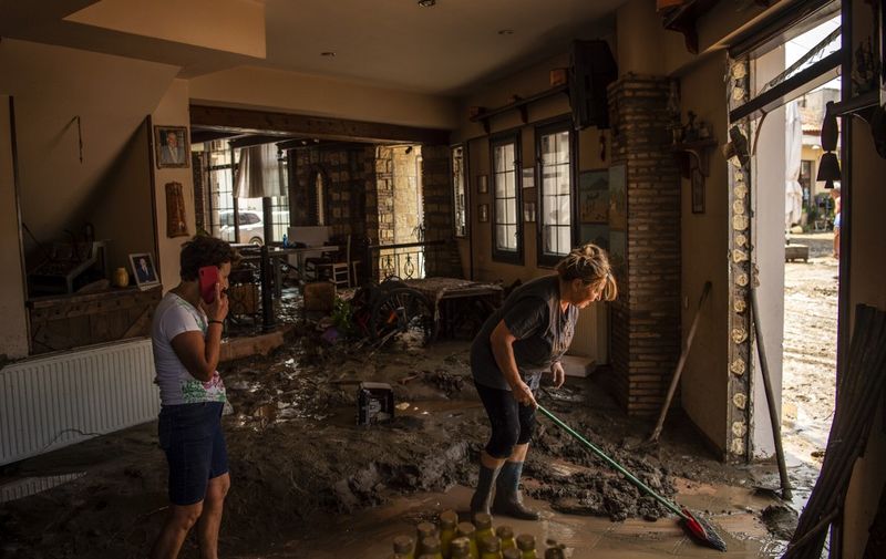 People try to move away water and mud from their shop, following a storm at the village of Politika, on Evia island, northeast of Athens, on August 9, 2020. - Five people including a baby died and two more were missing as torrential rains and floods swept the Greek island of Evia, damaging dozens of houses and blocking roads, officials said on August 9. (Photo by ANGELOS TZORTZINIS / AFP)