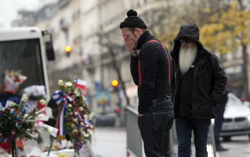 Singer of the US rock group Eagles of Death metal Jesse Hughes (L) and guitarist Dave Catching pay tribute to the victims of the November 13 Paris terrorist attacks at a makeshift memorial in front of the Bataclan concert hall on December 8, 2015 in Paris. 
The Eagles of Death Metal band returned to the Bataclan concert hall in Paris, nearly a month after they survived a jihadist attack there in which 90 people died. / AFP / MIGUEL MEDINA