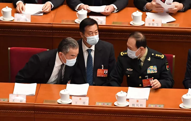 China's Foreign Minister Wang Yi (L) speaks with China's Defense Minister Wei Fenghe (R) before the second plenary session of the National People's Congress (NPC) at the Great Hall of the People in Beijing on March 8, 2022. (Photo by Leo RAMIREZ / AFP)