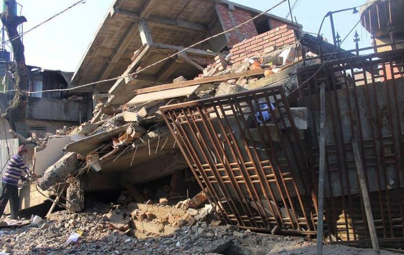 An Indian man stands at a collapsed building following a 6.7 magnitude earthquake, in Imphal on December 4, 2015.  At least eight people were killed and scores injured January 4, when a strong 6.7 magnitude earthquake struck northeast India, sending panicked residents fleeing into the streets even hundreds of kilometres away in Bangladesh.   AFP PHOTO/ MANIPUR TIMES / AFP / MANIPUR TIMES