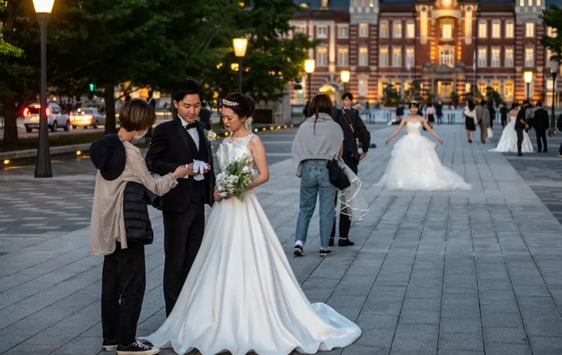 People prepare for a wedding photo shoot near Tokyo station during evening hour in Tokyo on May 23, 2021. (Photo by Philip FONG / AFP)