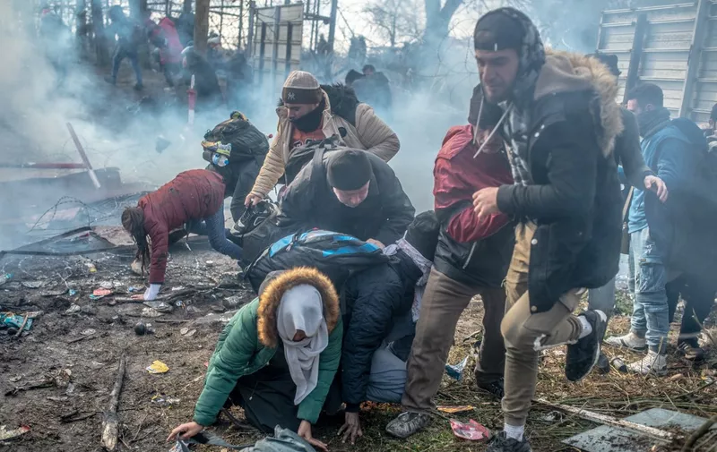 Migrants run from tear gas during clash with Greek police on the buffer zone Turkey-Greece border, at Pazarkule, in Edirne district, on February 29, 2020. - Thousands of migrants stuck on the Turkey-Greece border clashed with Greek police on February 29, 2020, according to an AFP photographer at the scene. Greek police fired tear gas at migrants who have amassed at a border crossing in the western Turkish province of Edirne, some of whom responded by hurling stones at the officers. The clashes come as Greece bolsters its border after Ankara said it would no longer prevent refugees from crossing into Europe following the death of 33 Turkish troops in northern Syria. (Photo by BULENT KILIC / AFP)