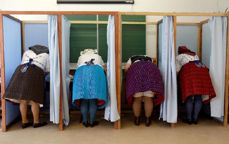 Women dressed in traditional Hungarian outfit prepare their votes in a polling station in a school in Veresegyhaz, some 30kms east of Budapest, on April 8, 2018, during the general election. 
Hungary votes in parliamentary elections on April 8, 2018 that will decide whether nationalist Prime Minister Viktor Orban wins an expected third consecutive term. / AFP PHOTO / PETER KOHALMI