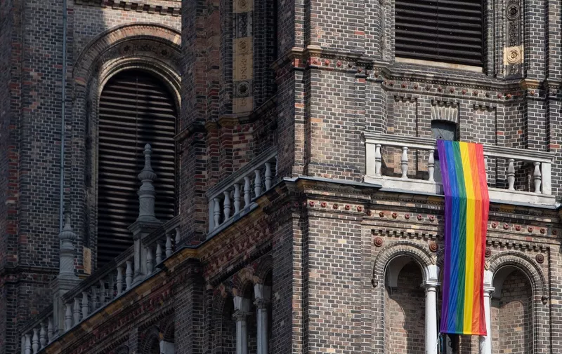 A LGBT rainbow flag hangs from on the steeple of the parish church in the Breitenfeld quarter in Vienna, on March 25, 2021. - The Catholic church of the parish of Hard is one of many in Austria which decided to fly the rainbow flag in solidarity with the LGBT community after the Vatican ruled last month that the Church couldn't bless same-sex partnerships. (Photo by ALEX HALADA / AFP) / TO GO WITH AFP STORY OF JASTINDER KHERA