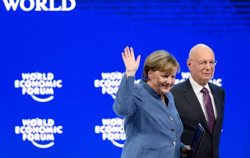 German chancellor Angela Merkel (L) waves next to Founder and Executive Chairman of the World Economic Forum (WEF) Klaus Schwab after addressing the annual World Economic Forum (WEF) on January 24, 2018 in Davos, eastern Switzerland. (Photo by Fabrice COFFRINI / AFP)
