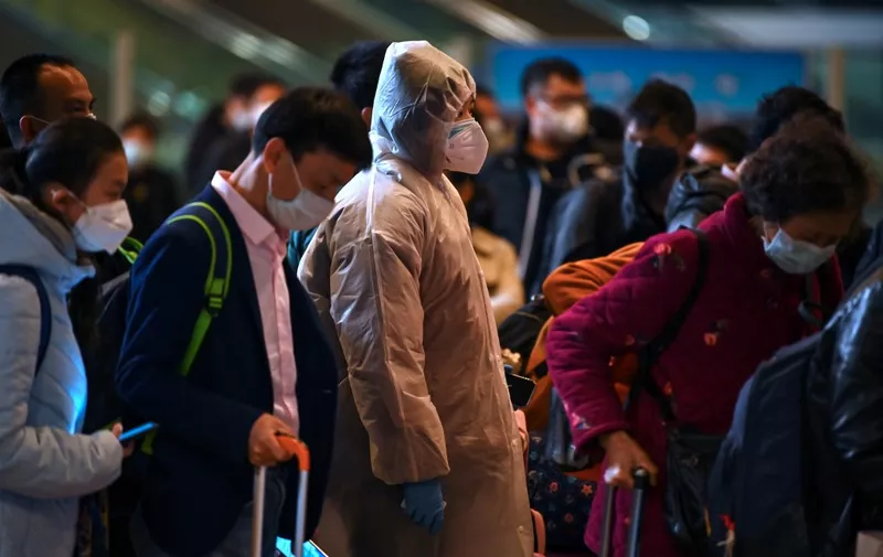 Mask-clad passengers wait in a line after arriving at the railway station in Wuhan, China's central Hubei province on March 28, 2020, after travel restrictions into the city were eased following two months of lockdown due to the COVID-19 coronavirus outbreak. - The Chinese city of 11 million people that was Ground Zero for what became the global coronavirus pandemic partly reopened on March 28 after more than two months of almost total isolation. (Photo by HECTOR RETAMAL / AFP)