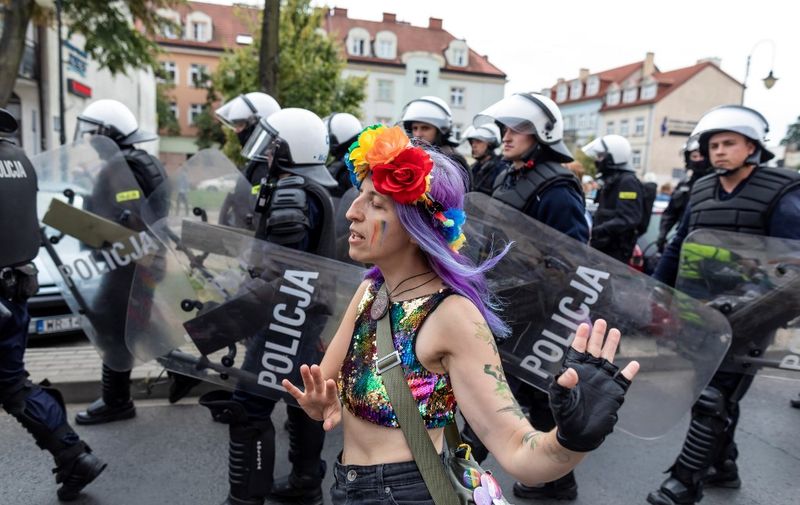 A participant walks past policemen during the first gay pride organised in Plock, central Poland, amidst risks of disruption by far-rights opponents on August 10, 2019. - Homosexuality is a frequent topic of public debate in the EU member, whose conservative ruling party leader Jaroslaw Kaczynski condemned gay rights as a "threat" in April. (Photo by Wojtek RADWANSKI / AFP)