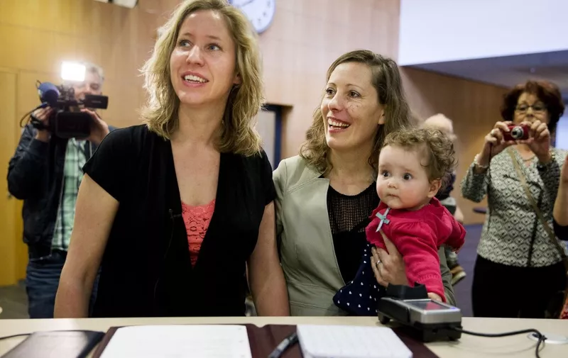 Corine (L) and Audrey Schep sign, along with their child Dieuwke, the first certificate of approvalthe first certificate of approval for a co-mother at the Zwolle city hall, The Netherlands, on April 1, 2014. Lesbian couples are now able to be both legal parents of a child of one of them, without going through complicated and costly procedures. AFP PHOTO / ANP - JERRY LAMPEN = netherlands out (Photo by JERRY LAMPEN / ANP / AFP)