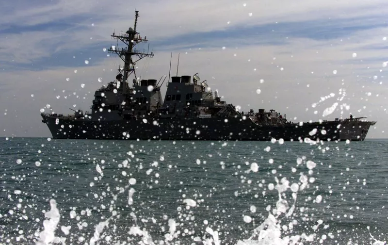 Water splashes as a rib boat carrying armed US navy sailors makes its way back to the USS Milius (in picture), some 20 miles (33 kilometers) off the Iraqi coastline, after patrolling 08 January 2003 the international waters of the northern Gulf as part of maritime interception operations (MIO). The primary mission of the USS Milius is to enforce UN sanctions against Iraq, but the Aegis guided missile destroyer is also ready to respond to any threat from Iraq.    AFP PHOTO/Leila GORCHEV (Photo by LEILA GORCHEV / AFP)