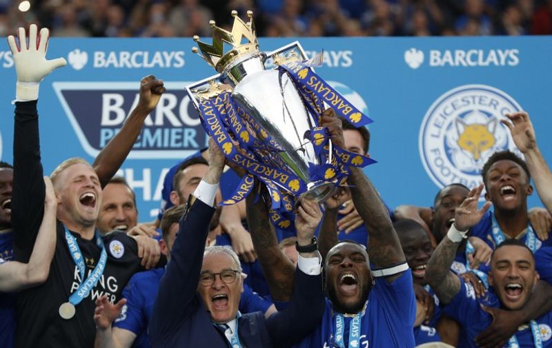 Leicester City's Italian manager Claudio Ranieri (C) and Leicester City's English defender Wes Morgan hold up the Premier league trophy after winning the league and the English Premier League football match between Leicester City and Everton at King Power Stadium in Leicester, central England on May 7, 2016. / AFP PHOTO / ADRIAN DENNIS / RESTRICTED TO EDITORIAL USE. No use with unauthorized audio, video, data, fixture lists, club/league logos or 'live' services. Online in-match use limited to 75 images, no video emulation. No use in betting, games or single club/league/player publications.  /