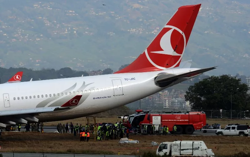 Nepalese rescue workers check the area around a Turkish Airlines plane after it slid off the tarmac at Kathmandu international airport on March 4, 2015.  A Turkish Airlines plane carrying 224 passengers had to be evacuated after it missed the runway on landing at Kathmandu airport and skidded onto nearby grassland.  AFP PHOTO / PRAKASH MATHEMA / AFP / PRAKASH MATHEMA