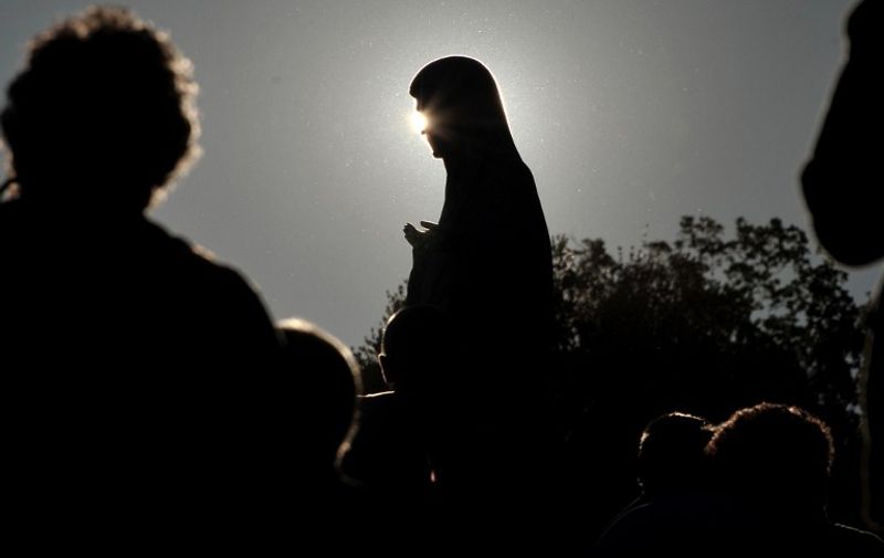 Catholic pilgrims pray near a statue of Virgin Mary on June 25, 2011 outside the Medjugorje church in the southern Bosnian village of Medjugorje. Almost one million people visit Medjugorje each year, where the Virgin Mary is said to have appeared to six young villagers for the first time on June 24, 1981. For 30 years, the alleged phenomenon was ignored by Roman Catholic authorities until 2010, when Pope Benedict XVI issued an order to form an investigation team to search for the truth in case of Medjugorje sightings. AFP PHOTO / ELVIS BARUKCIC / AFP PHOTO / ELVIS BARUKCIC