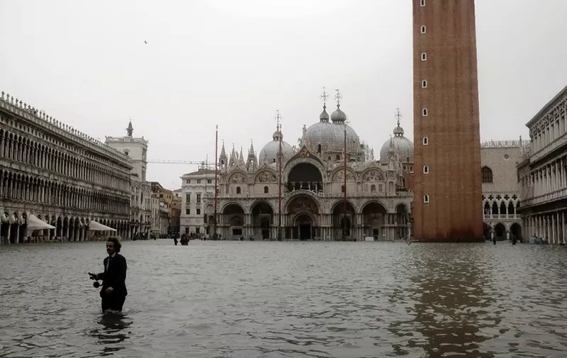 A man walks in the flooded St. Mark's Square during a high-water (Acqua Alta) alert in Venice on October 29, 2018 - The flooding, caused by a convergence of high tides and a strong Sirocco wind, reached around 150 centimetres on October 29. (Photo by MIGUEL MEDINA / AFP)