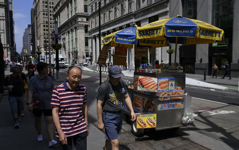 People walk past a hot dog vendor on July 12, 2022 in New York City. (Photo by ANGELA WEISS / AFP)