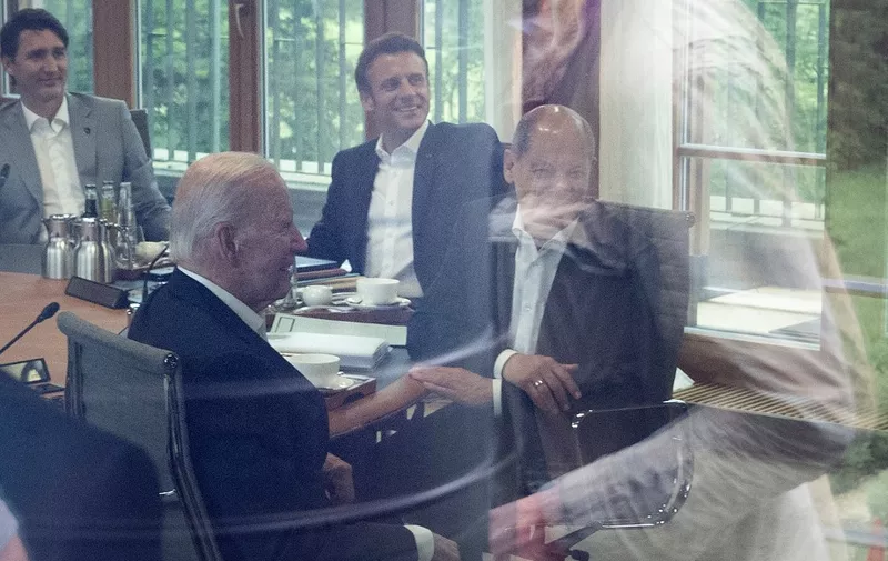 (L-R) Canadian Prime Minister Justin Trudeau, US President Joe Biden, France's President Emmanuel Macron and German Chancellor Olaf Scholz react as they attend a working session pictured through a window glass during the G7 leaders summit at Bavaria's Schloss Elmau castle, near Garmisch-Partenkirchen on June 28, 2022 on the last day of the G7 Summit. - During the summit running from June 26 to 28, 2022, G7-leaders are to discuss their united front against Russia and troubling weakness in the world economy. (Photo by Brendan Smialowski / POOL / AFP)