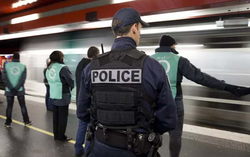 A picture taken on December 30, 2015 a police officer and members of the RATP security at work at the RER Auber station in Paris.   / AFP / KENZO TRIBOUILLARD