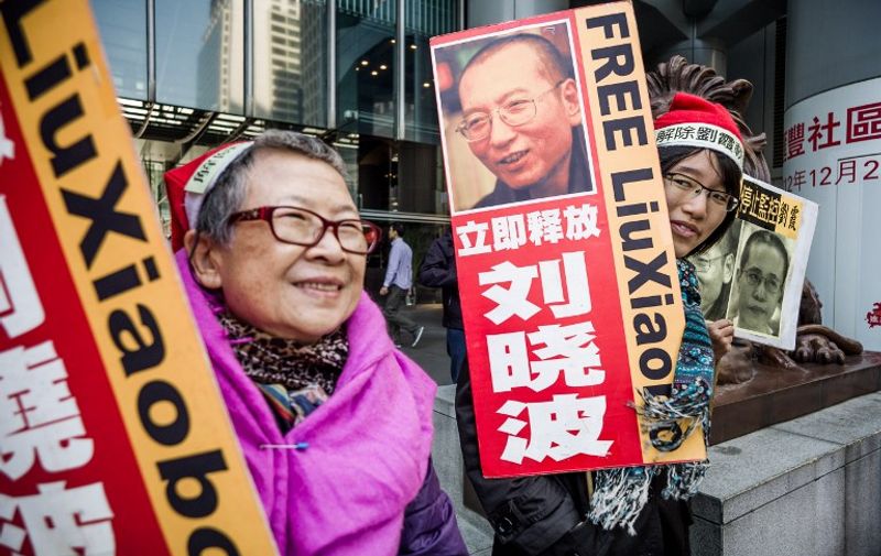 Members of the Hong Kong Alliance in Support of Patriotic Democratic Movements of China hold placards before they march to the central post office to mail a Christmas parcel to China's jailed Nobel Peace Prize laureate Liu Xiaobo, in Hong Kong on December 10, 2012. Liu Xiaobo was sentenced to 11 years in jail in December 2009 for "subversion" after co-authoring Charter 08, a bold petition calling for political reform in one-party Communist-ruled China.  AFP PHOTO / Philippe Lopez / AFP / PHILIPPE LOPEZ