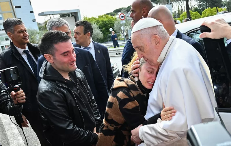Pope Francis hugs Serena Subania as her husband Matteo Rugghia (L) reacts, a couple who lost their five-year-old child a day earlier, as the Pope leaves the Gemelli hospital on April 1, 2023 in Rome, after being discharged following treatment for bronchitis. - The 86-year-old pontiff was admitted to Gemelli hospital on March 29 after suffering from breathing difficulties. (Photo by Filippo MONTEFORTE / AFP)