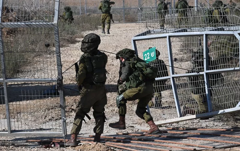 Israeli soldiers patrol a border fence gate with the Gaza Strip on October 15, 2023. In the eight days since Hamas gunmen killed more than 1,300 Israelis in a surprise attack, Israel has responded with a bombing campaign that has claimed over 2,300 lives in Gaza. (Photo by YURI CORTEZ / AFP)