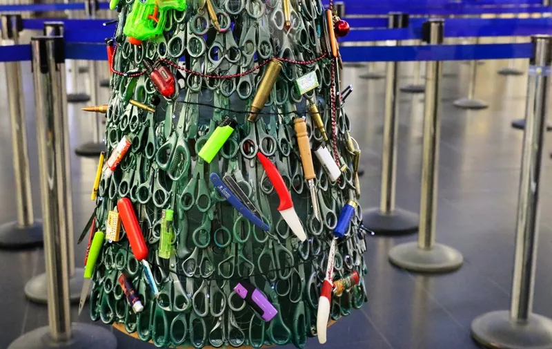 A "Christmas tree" deftly made and decorated using items that passengers had to leave behind during screening is on display at the airport departures' hall of Vilnius Airport in Vilnius, Lithuania, on December 12, 2019. - Staff at the Lithuanian airport in Vilnius came up with a sharp idea to remind travellers that safety comes first: a Christmas tree made of confiscated knives and toy guns. (Photo by Petras Malukas / AFP)