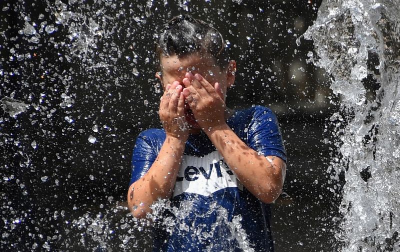 A child cools off under water jets in a fountain during a heatwave in Montpellier,  southern France, on June 27, 2019. - Forecasters say Europeans will feel sizzling heat this week with temperatures soaring as high as 40 degrees Celsius (104 degrees Fahrenheit) in an "unprecedented" June heatwave hitting much of Western Europe. (Photo by Pascal GUYOT / AFP)