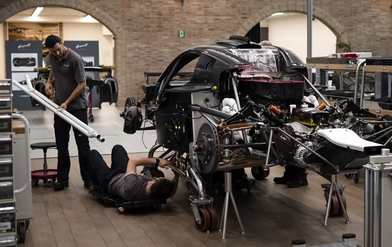 Workers assemble a new car at the factory of Italian manufacturer of luxury sports cars Pagani, on May 27, 2022 in San Cesario sul Panaro, near Modena, Northern Italy. - If Tuscany has Chianti, the Italian region of Emilia-Romagna has "Motor Valley", an area that boasts one of the highest concentrations of luxury sports cars and motorbikes in the world. The so-called Land of Motors, covering around 1,000 square kilometres of prime agricultural land roughly between Bologna and Modena, is home to Lamborghini and Ferrari, Maserati and Ducati, in addition to less well-known brands. (Photo by MARCO BERTORELLO / AFP)
