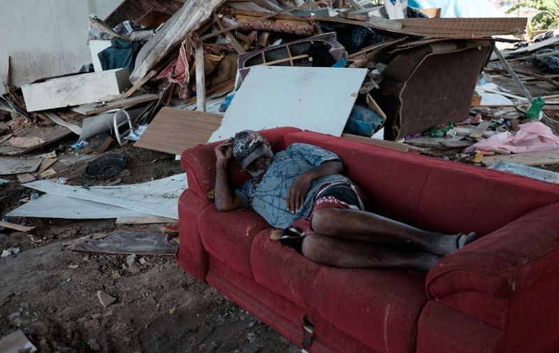 A man sleeps on a sofa after his shanty was demolished following an order from the city hall to demolish about 40 shacks under a flyover in Rio de Janeiro, Brazil, on April 28, 2015, two years after a huge fire burnt the place down and left 240 families homeless.   AFP PHOTO / YASUYOSHI CHIBA