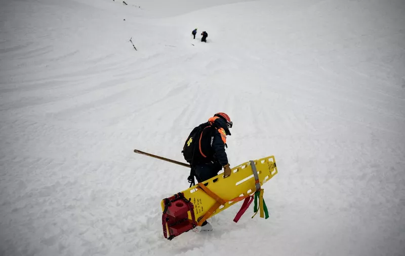 A rescuer carries a stretcher during a search and rescue exercise for avalanche victims in the French Alps ski resort of Les Deux Alpes, south-eastern France on December 20, 2023. (Photo by JEFF PACHOUD / AFP)