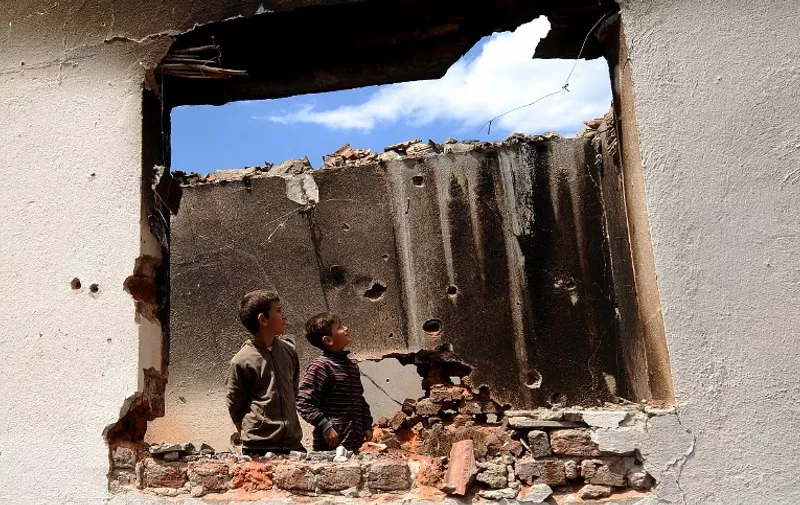 Two boys look inside a destroyed house in Kumanovo on May 12, 2015. Special police units pulled out of the northern Macedonian town early on May 11 where 22 people, including eight officers, were killed over the weekend in worst violence in the country since its 2001 inter-ethnic conflict. Thirty men were later charged with terror offences.  AFP PHOTO / ROBERT ATANASOVSKI