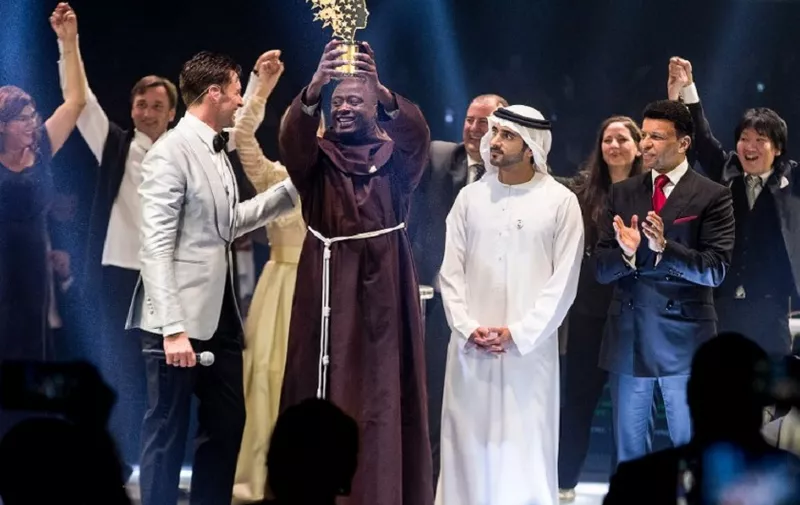This handout picture provided on March 24, 2019 by the Global Education and Skills Forum, an initiative of the Varkey Foundation, shows Kenyan teacher Peter Tabichi (C) holding up the Global Teacher Prize (GTP) trophy after winning the US$ 1 million award during an official ceremony in Dubai presented by Australian actor Hugh Jackman (C-L) and attended by the Dubai Crown Prince Hamdan bin Mohammed Al-Maktoum (C-R). - Tabichi, a 36-year-old maths and physics from a secondary school in a remote village in Kenya's Rift Valley, who organisers say gives away 80 percent of his monthly income to the poor, received the prize at a ceremony on March 24. (Photo by - / Global Education and Skills Forum / AFP) / RESTRICTED TO EDITORIAL USE - MANDATORY CREDIT "AFP PHOTO / GLOBAL EDUCATION AND SKILLS FORUM" - NO MARKETING NO ADVERTISING CAMPAIGNS - DISTRIBUTED AS A SERVICE TO CLIENTS