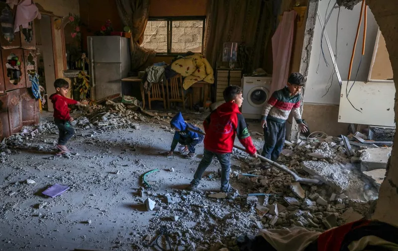 Palestinian children collect small pieces of debris following Israeli bombardment in Rafah in the southern Gaza Strip on December 22, 2023, amid continuing battles between Israel and the militant group Hamas. (Photo by Mohammed ABED / AFP)