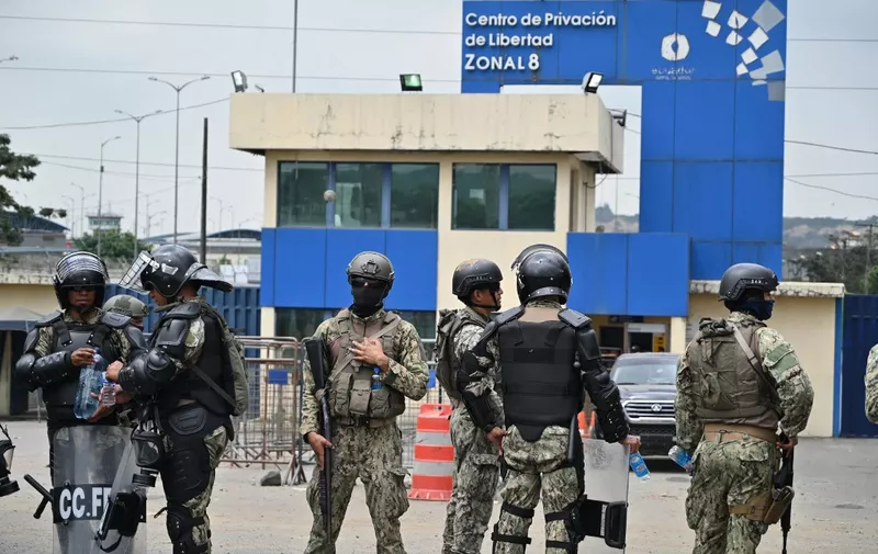 Members of the Ecuadorean Armed Forces stand guard outside the Zonal Penitentiary No. 8 as inmates protest, demanding the return to this prison of the leader of the "Los Choneros" gang, alias Fito, in Guayaquil, Ecuador, on August 14, 2023. Alias Fito was transferred on Saturday, August 12 to La Roca, a maximum-security prison within the same penitentiary complex. (Photo by STRINGER / AFP)