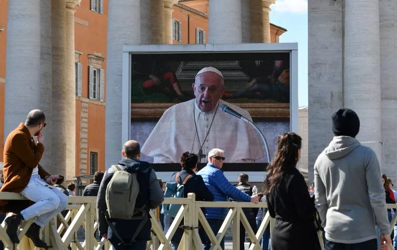 People watch a screen live-broadcasting Pope Francis' Sunday Angelus prayer on St. Peter's Square at the Vatican on March 8, 2020, after millions of people were placed under forced quarantine in northern Italy as the government approved drastic measures in an attempt to halt the spread of the COVID-19 outbreak, caused by the novel coronavirus that is sweeping the globe. - On top of the forced quarantine of 15 million people in vast areas of northern Italy until April 3, the government has also closed schools, nightclubs and casinos throughout the country, according to the text of the decree published on the government website. With more than 230 fatalities, Italy has recorded the most deaths from the COVID-19 disease of any country outside China, where the outbreak began in December. (Photo by Alberto PIZZOLI / AFP)