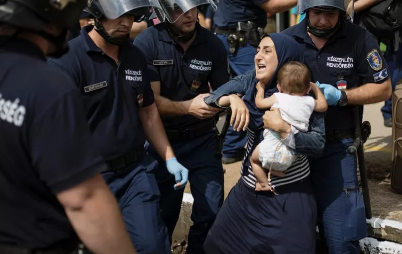 A migrant family is arrested by local police after their local train coming from Budapest and heading to the Austrian border has been stopped in Bicske, west of the Hungarian capital on September 3, 2015. The train carrying between 200 and 300 migrants left Budapest's main international train station after authorities re-opened the station to migrants as the EU is grappling with an unprecedented influx of people fleeing war, repression and poverty in what the bloc has described as its worst refugee crisis in 50 years. AFP PHOTO / ISTVAN BIELIK