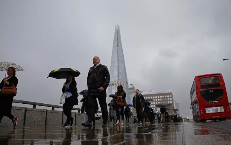 Commuters heading into the City of London walk in the rain across London Bridge, in front of the Shard skyscraper, in central London on June 27, 2016. 
Britain should only trigger Article 50 to leave the EU when it has a "clear view" of how its future in the bloc looks, finance minister George Osborne said Monday following last week's shock referendum. / AFP PHOTO / ODD ANDERSEN