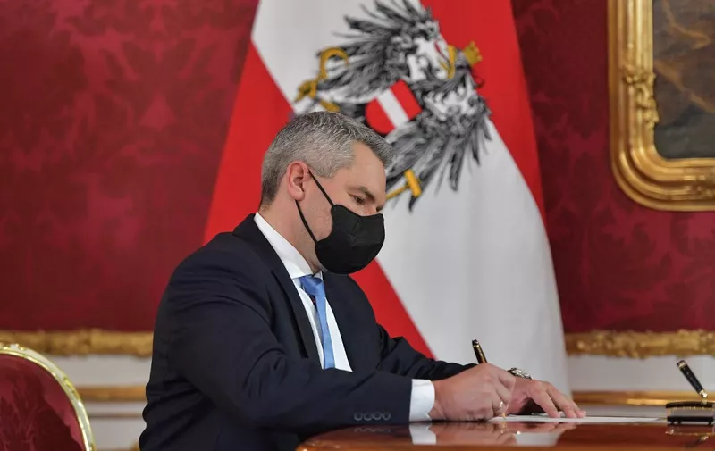 Newly appointed Austria's Chancellor Karl Nehammer signs his certificate of appointment during a swearing-in ceremony of the new Chancellor at the Presidential Hofburg palace in Vienna, Austria on December 6, 2021. - Austria's Interior Minister Karl Nehammer is due to be sworn in as the country's third chancellor in as many months on December 6, capping a turbluent few days in the country's politics. (Photo by JOE KLAMAR / AFP)