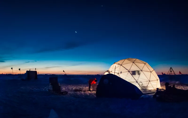 Researcher working at an ice camp under clear polar sky