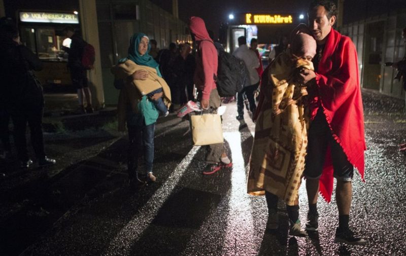 Migrants climb off buses at the Hungarian-Austrian border early in the morning on September 5, 2015 before they will walk to the Austrian village of Nickelsdorf from where they wish to head to Salzburg on the German-Austrian border. The first bus carrying migrants who have been stranded in the Hungarian capital reached the Austrian border early September 5, after Vienna and Berlin agreed to take in thousands of refugees desperate to start new lives in Western Europe. Some 2,500-3,000 migrants have entered Austria from Hungary in the past few hours, Austrian police said early September 5. AFP PHOTO/JOE KLAMAR