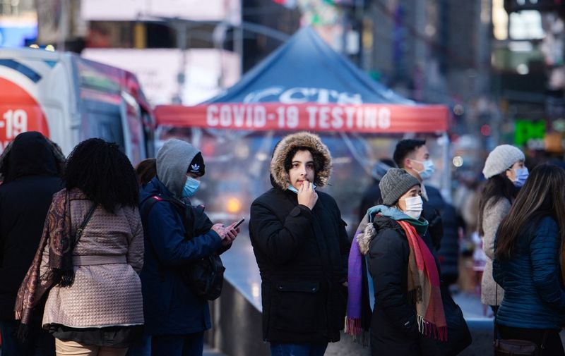 People queue at a street-side Covid-19 testing booth in New York's Times Square on December 20, 2021. - On December 18, New York state announced a record number of daily cases for the second day in a row with almost 22,000 positive results. (Photo by Ed JONES / AFP)